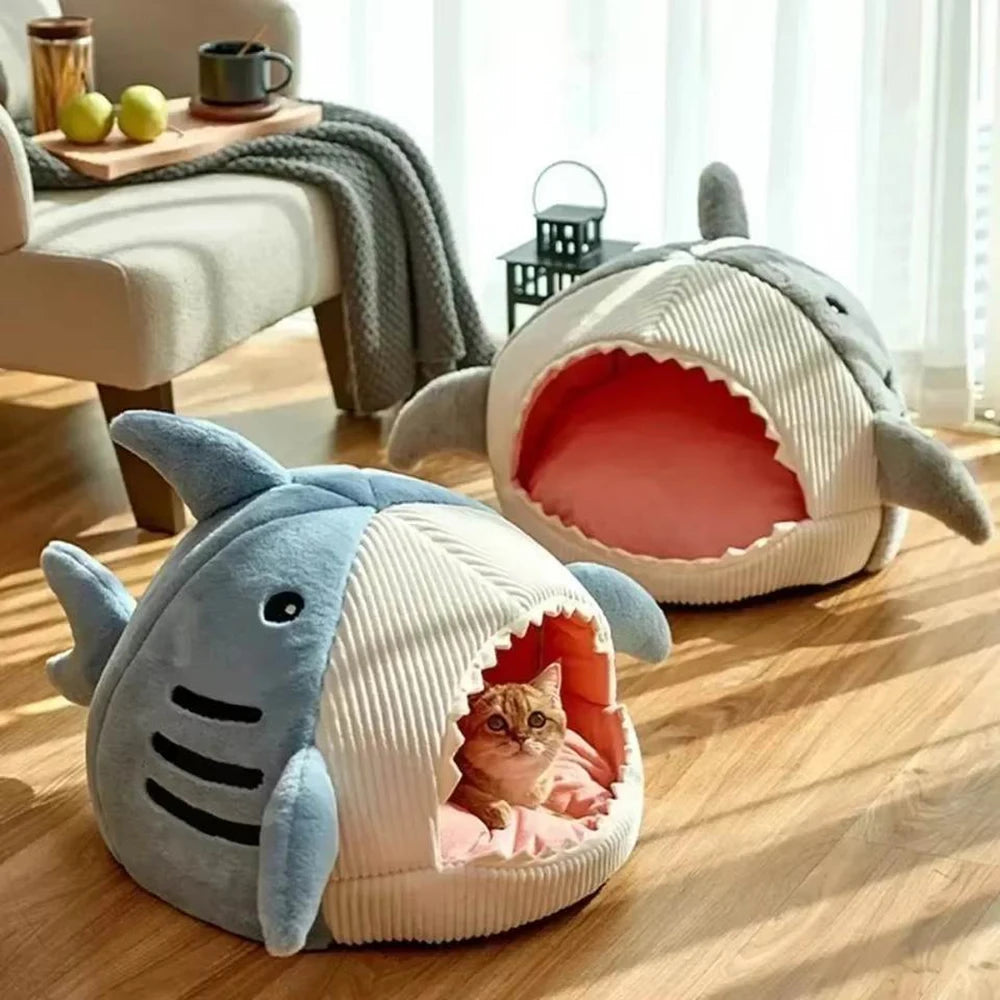 Two shark-shaped pet beds on a wooden floor with a cat inside one of them.