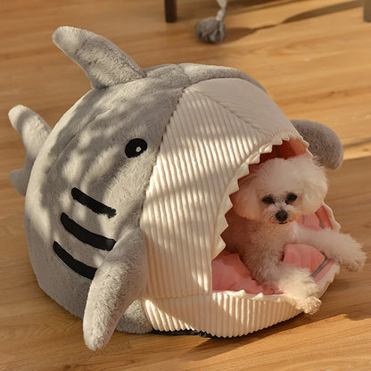 Dog inside a shark-shaped pet bed on a wooden floor
